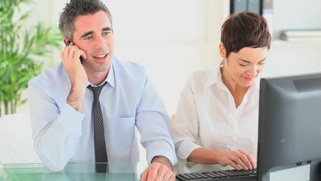 Businessman-on-the-phone-sitting-next-to-his-secretary