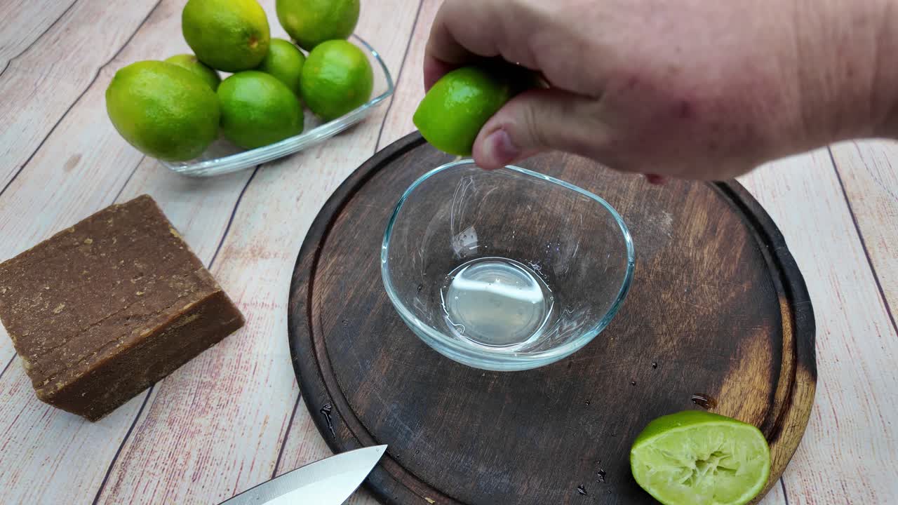 Close-up POV squeezing limes into bowl, wooden surface, fresh, juicy