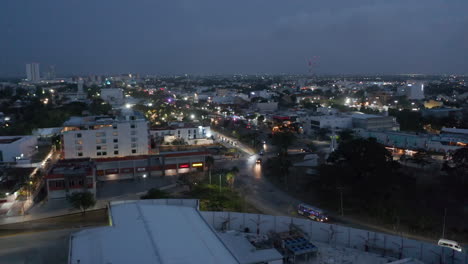 Fly-above-night-city.-Traffic-on-busy-multilane-road-leading-through-urban-neighbourhood.-Cancun,-Mexico