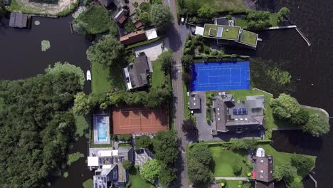 A-topdown-drone-shot-panning-forward,-over-a-small-road-with-houses-and-water-on-either-side,-in-the-Netherlands