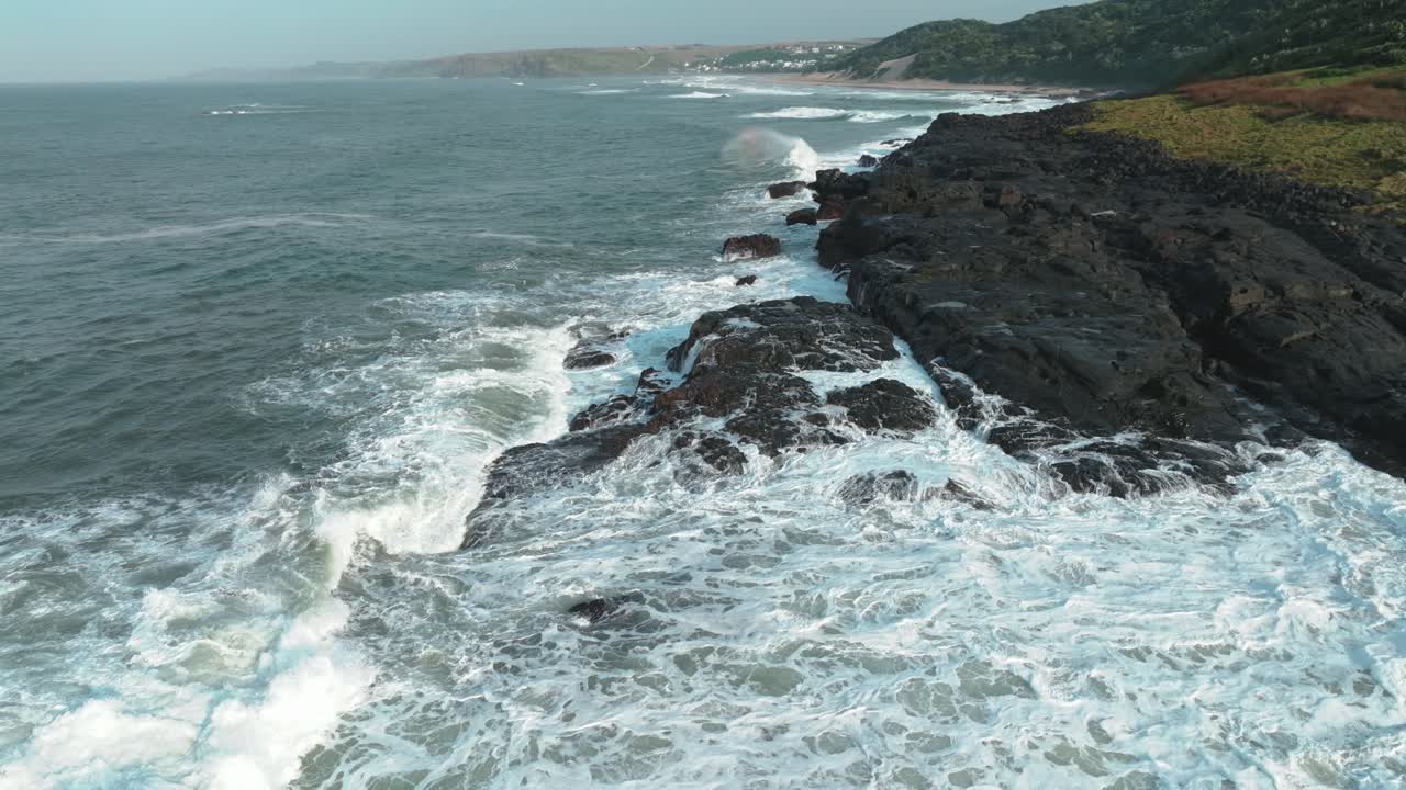 Ripresa aerea di onde che si infrangono sulle rocce costiere con un profilo laterale della costa di East London, in Sudafrica