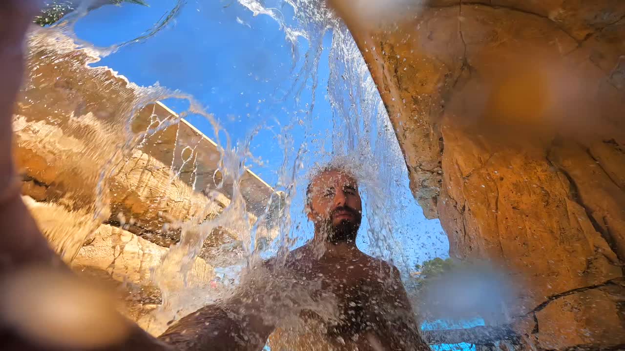 Man die geniet van een waterval in een zwembad