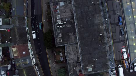 aerial top down tracking shot of unrecognizable black car driving through urban town setting