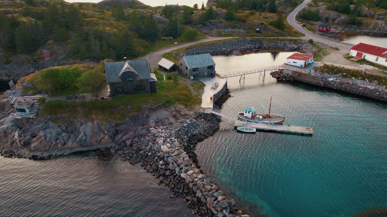 Norwegian island with red cabin, fishing boat and calm Arctic waters under soft evening light. Lofoten