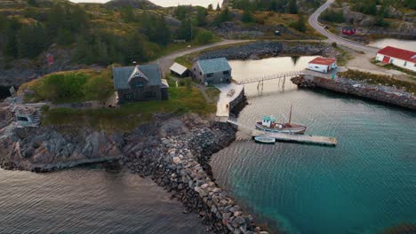 norwegian island with red cabin, fishing boat and calm arctic waters under soft evening light. lofoten