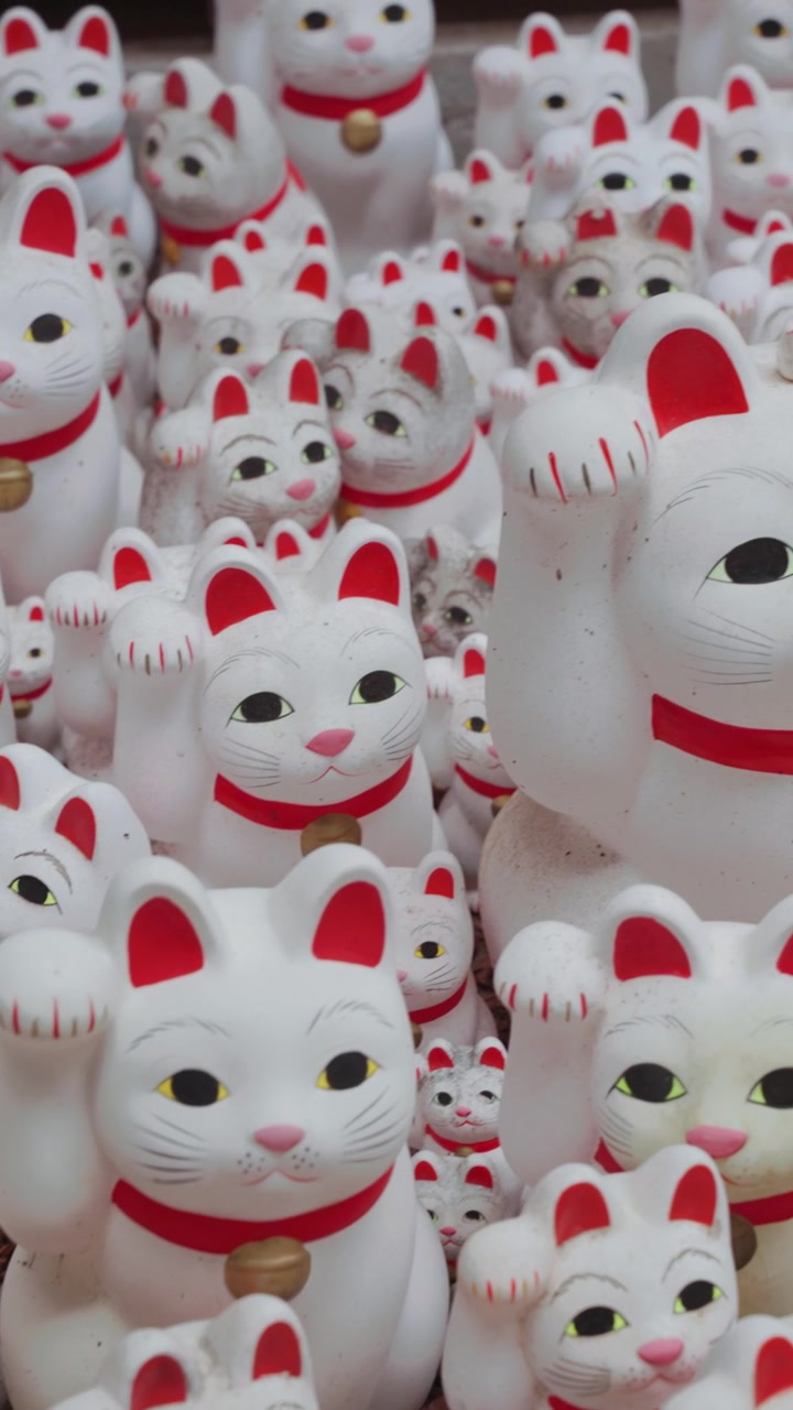 Primo piano verticale di molte iconiche statue di gatti portafortuna Maneki Neko al Tempio Gotokuji a Tokyo, che mostrano i simboli più famosi del paese di fortuna, prosperità e cultura tradizionale giapponese
