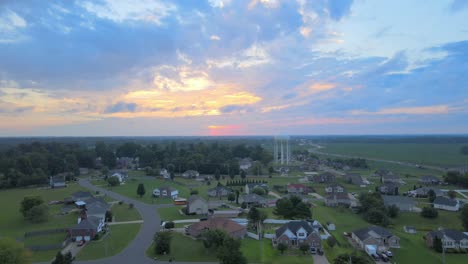 drone flying towards the watertower in clarksville with a bus on the road revealing a beautiful sunrise with clouds in the sky