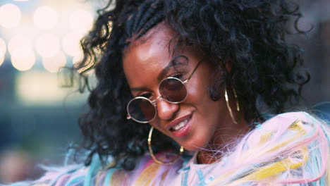 Young-black-woman-in-multicoloured-fringed-jacket-dancing-on-the-street,-close-up