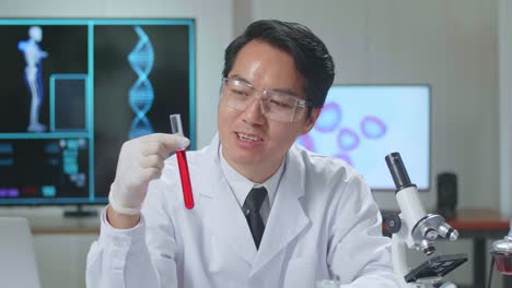 young asian male research scientist holding glass test tube and speaking to the camera