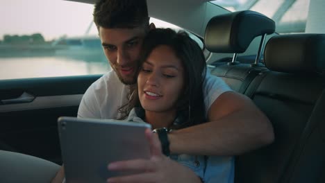 Couple using tablet in the back of the car