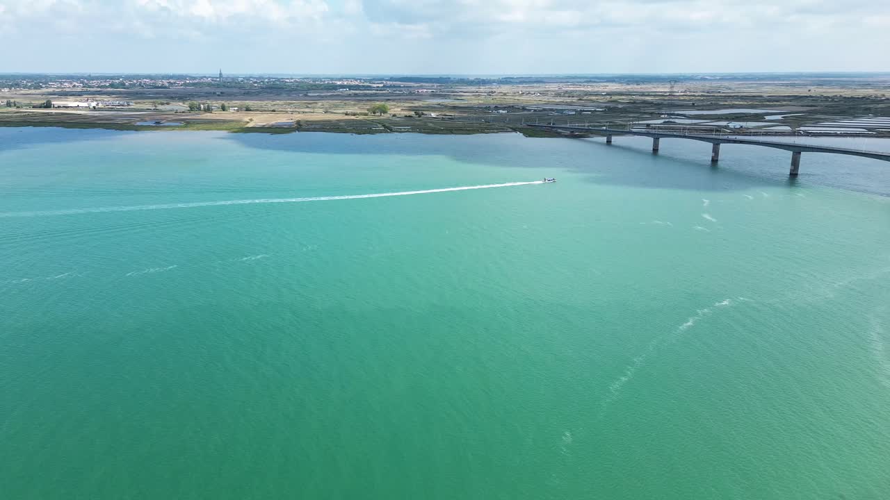 Aerial view of Île d’Oléron showcasing its vibrant landscapes, pine forests, oyster farms, and boats navigating along the calm Atlantic coast on a clear, sunny day