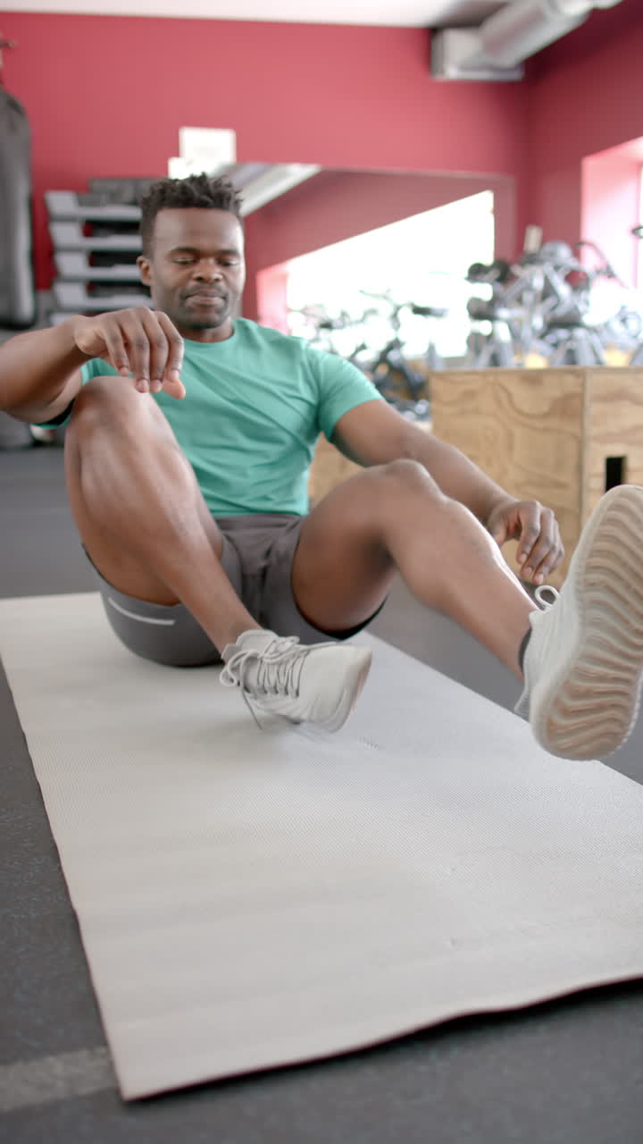 Vertical video: Exercising on yoga mat, strong and fit man performing sit-ups in gym