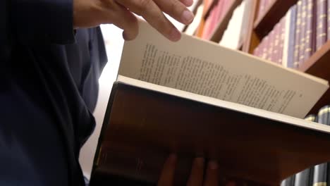 close-up low angle view of a person leafing through the pages of a book in a library or book store