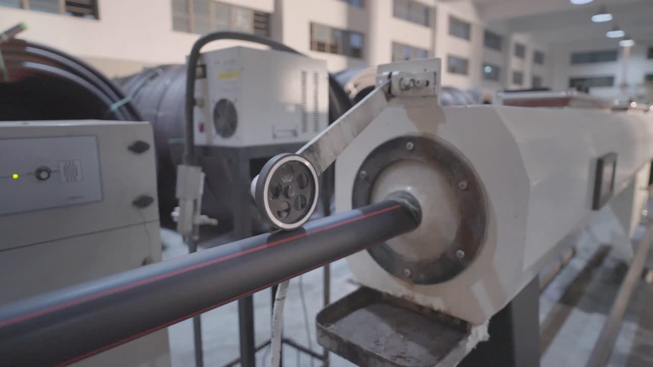 An industrial machine is crafting a black pipe with precision in a factory hall, showcasing advanced technology and manufacturing processes in a modern industrial setting.