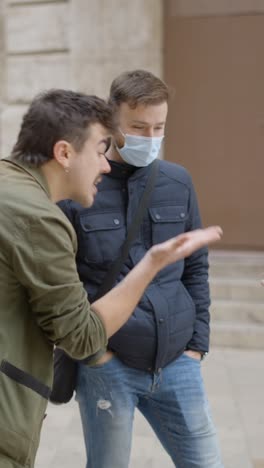 people wearing face masks interacting with playing cards on the street