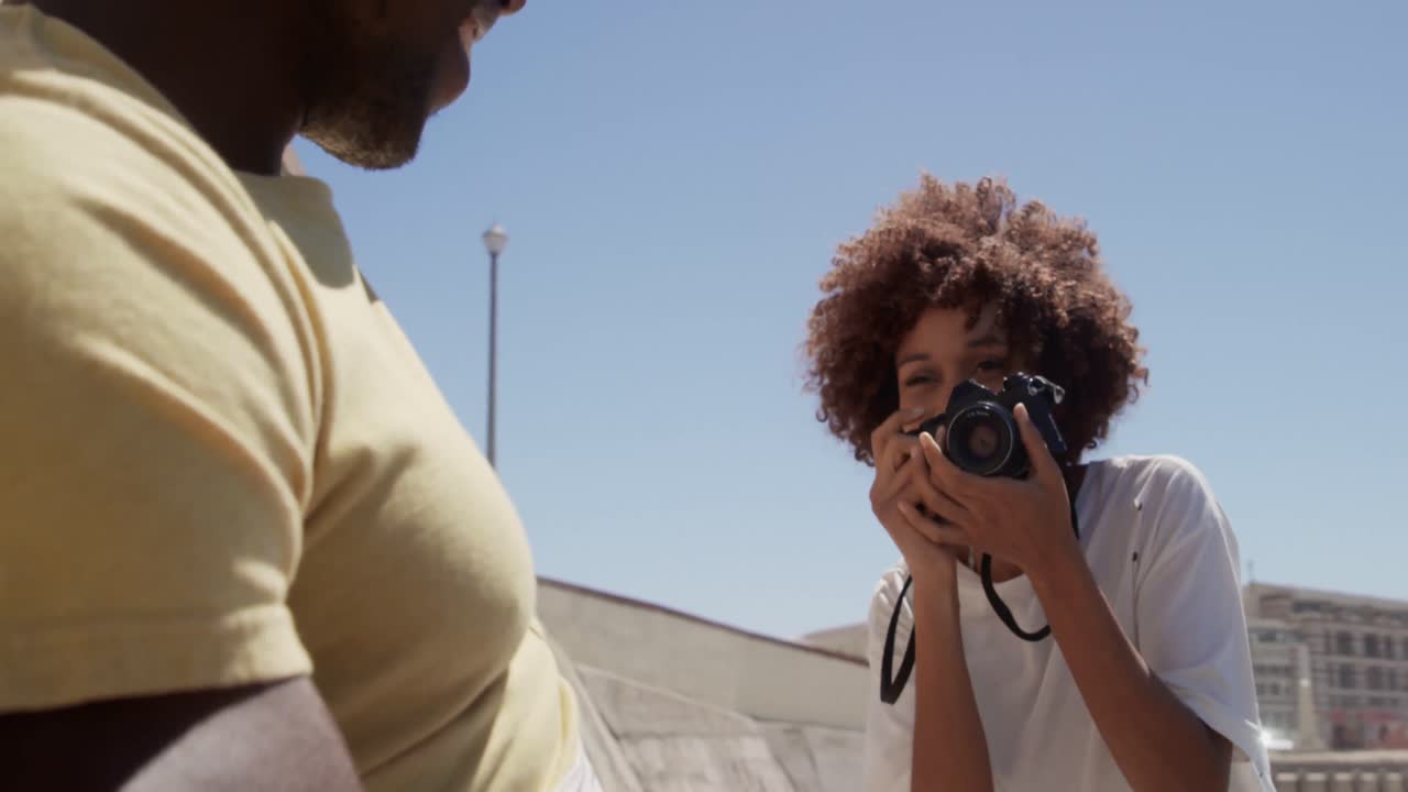 Woman taking photo of man with digital camera on the beach 4k