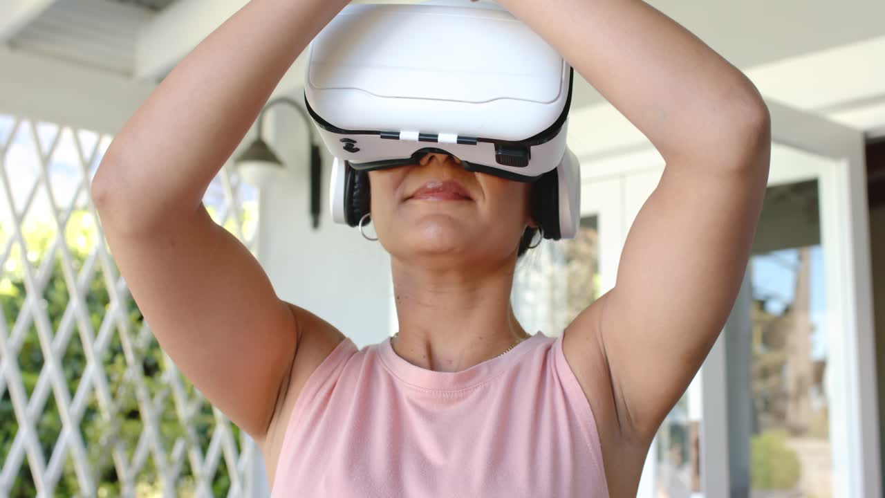 Guided VR meditation starting with woman wearing headset lowering arms and pressing palms on porch
