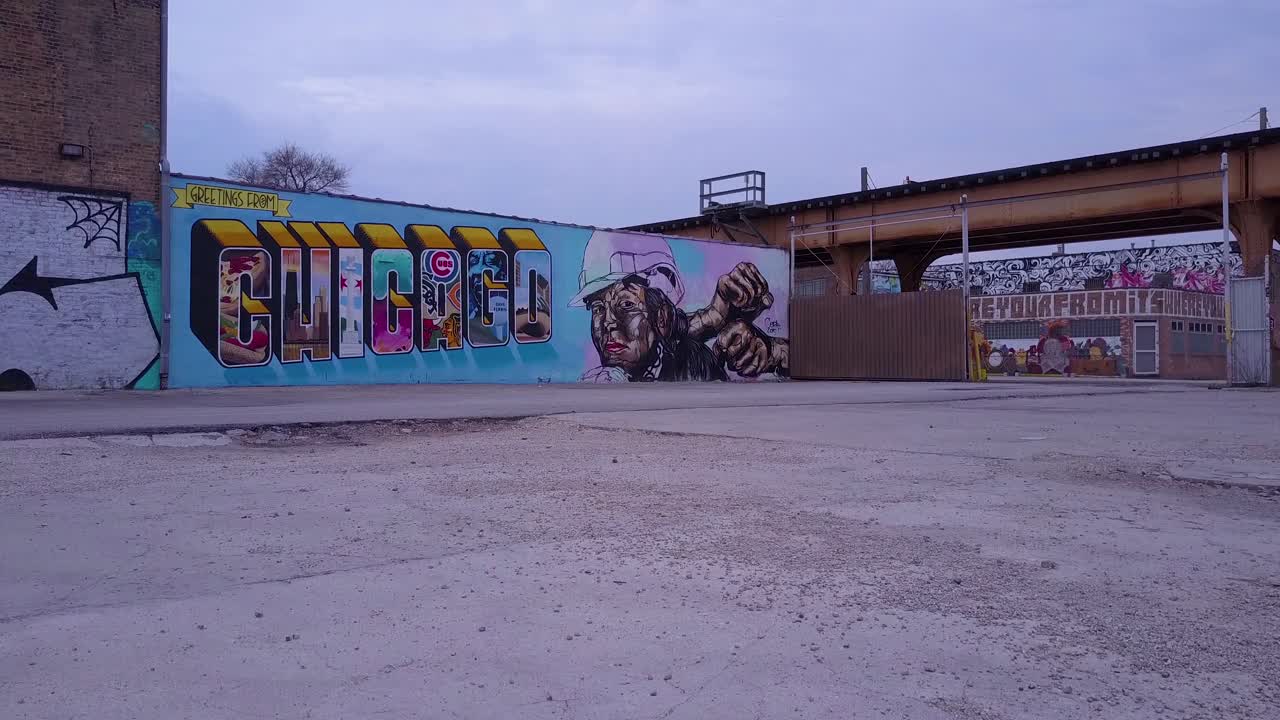 una antena que se eleva sobre un letrero del centro de chicago pintado en una pared mientras pasa el tren