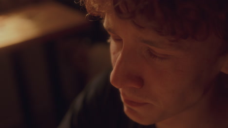 close-up of heartbroken young man crying in warmly lit room at home