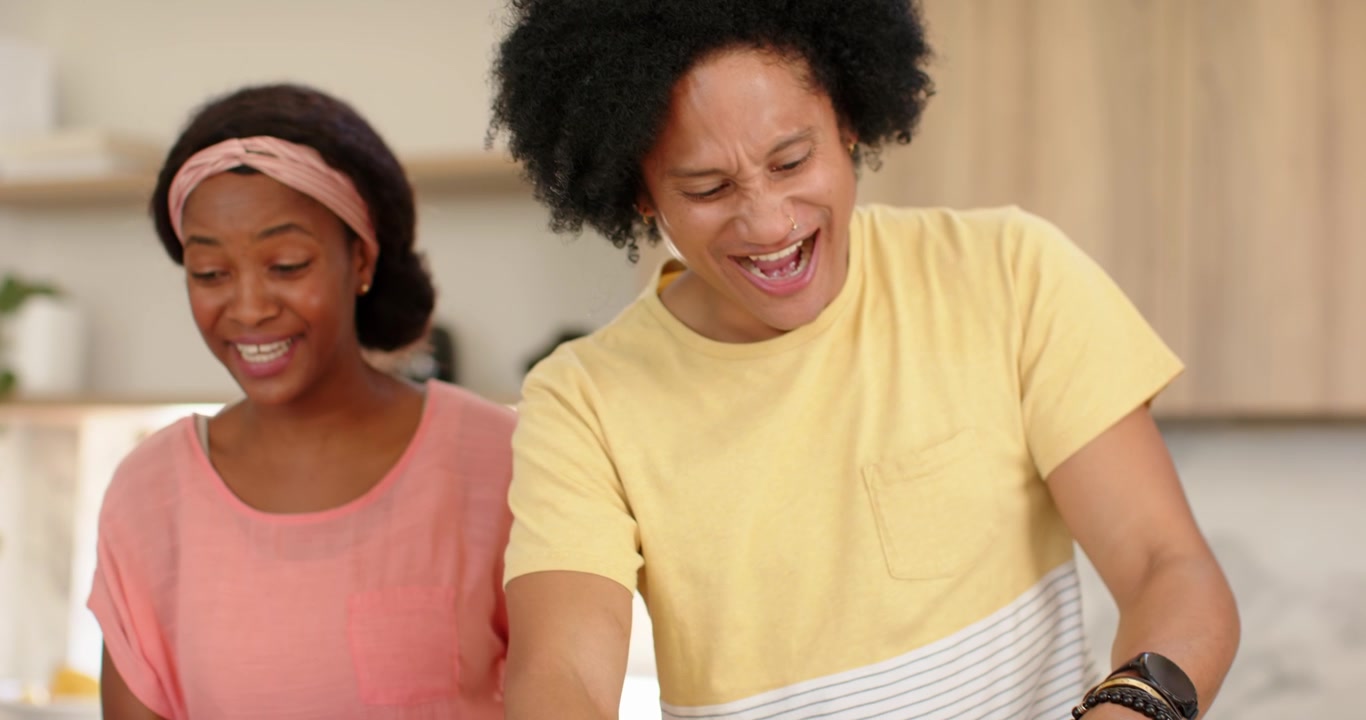 African American family smiling, man in yellow tee slicing fresh pizza with cutter onto plates