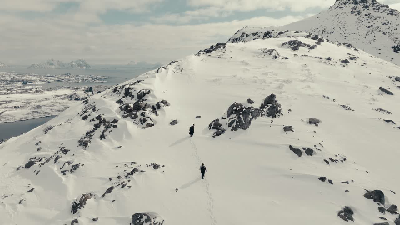 Hikers Trekking On Snowpack Mountains In The Lofoten Archipelago Near Svolvaer, Norway. Aerial Drone Shot