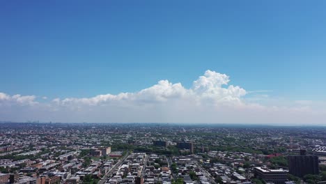 an aerial shot over brooklyn. the drone camera pedestal downward from high in the sky. the camera shows the horizon, white clouds and blue skies in the distance on a sunny day