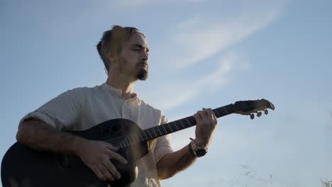 hombre tocando la guitarra acústica al aire libre