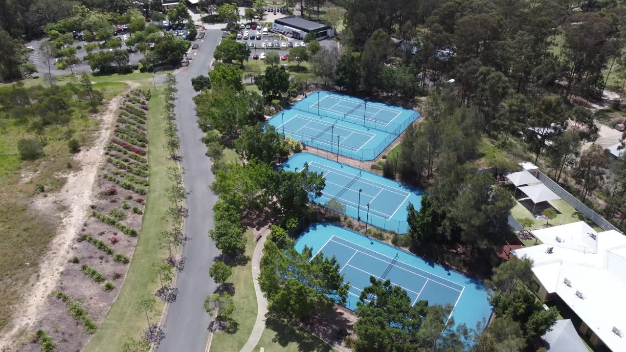 Drone ascending over four tennis courts showing a golf club house in the background in Australia