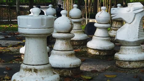 footage of large chess pieces abandoned in the park