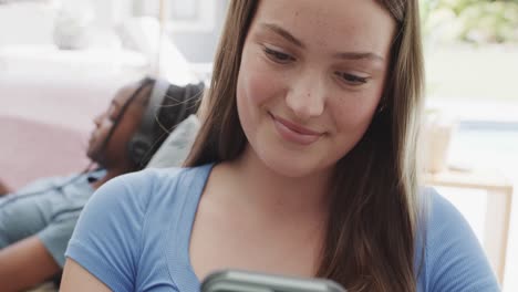 felices y diversas amigas adolescentes que usan auriculares y usan teléfonos inteligentes