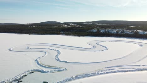 whole race track on a frozen lake in finland during golden hour – aerial winter landscape high altitude unveil shot