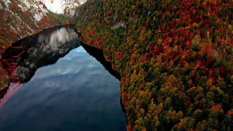 Toma-De-Drone-De-Una-Licencia-Cambiando-De-Color-Alrededor-De-Un-Lago-Montañoso