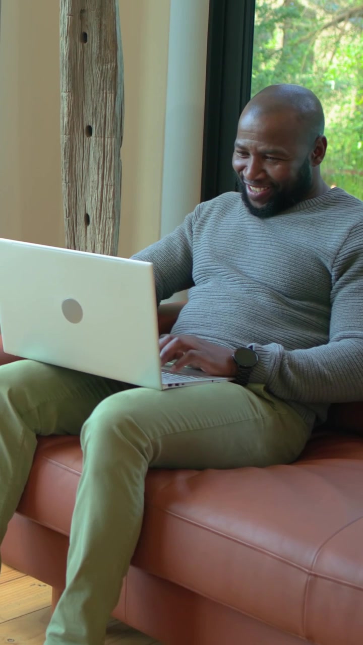 Vertikal video: Far taster, ser en laptop-advarsel, mens han arbejder, griner ved vinduet, barn på telefon.