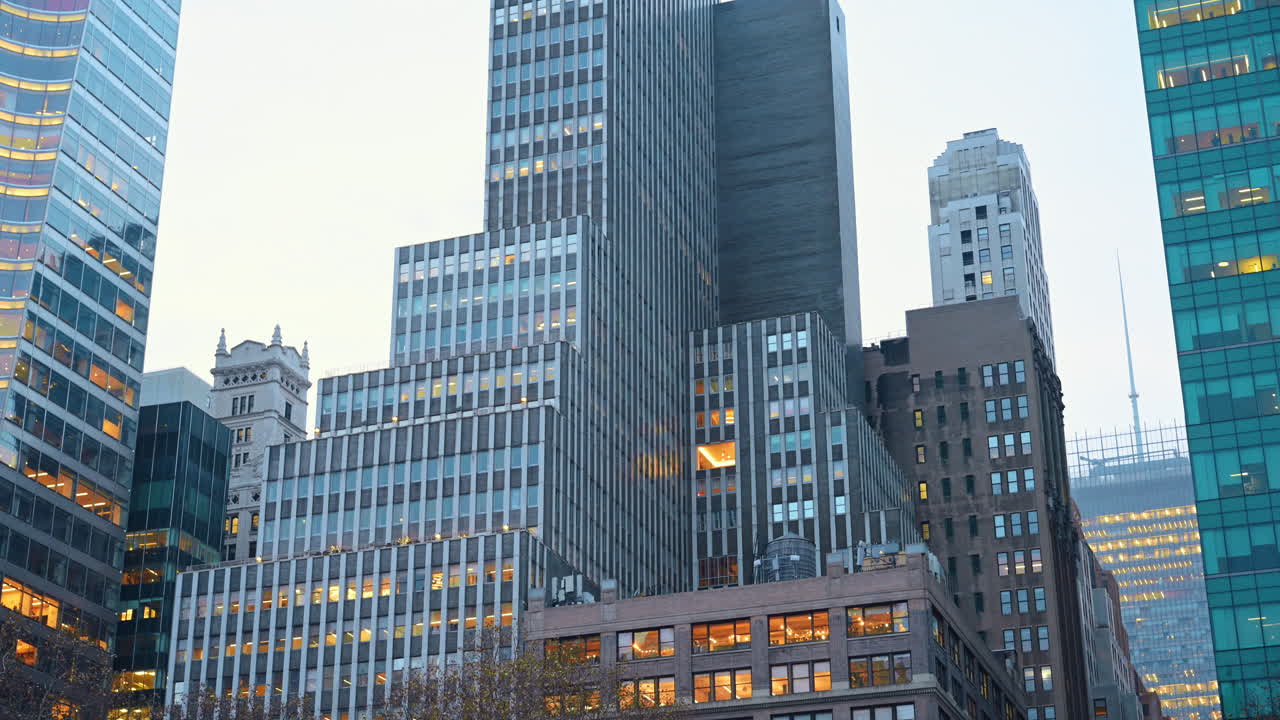 Edifícios com luzes ao entardecer no Bryant Park, Nova York, mostrando a agitação da cidade