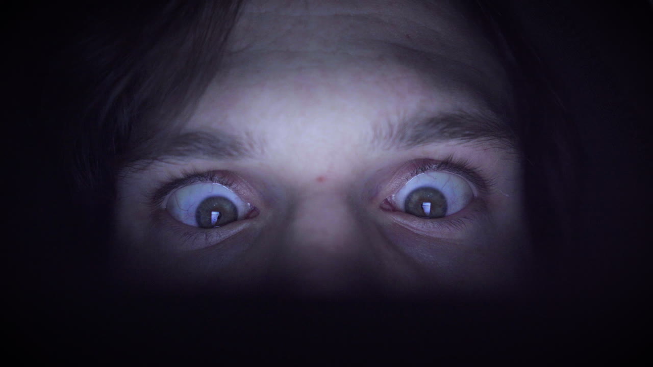 человек, одержимый прокруткой в темном помещении