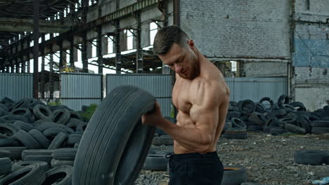 man training with tire. muscular fitness man training with old tire wheel