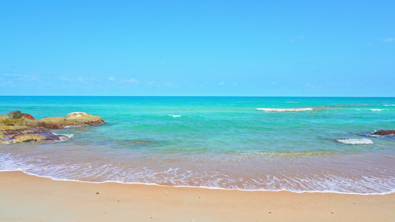 청록색 바다에서 빈 해변으로 파도가 밀려온다