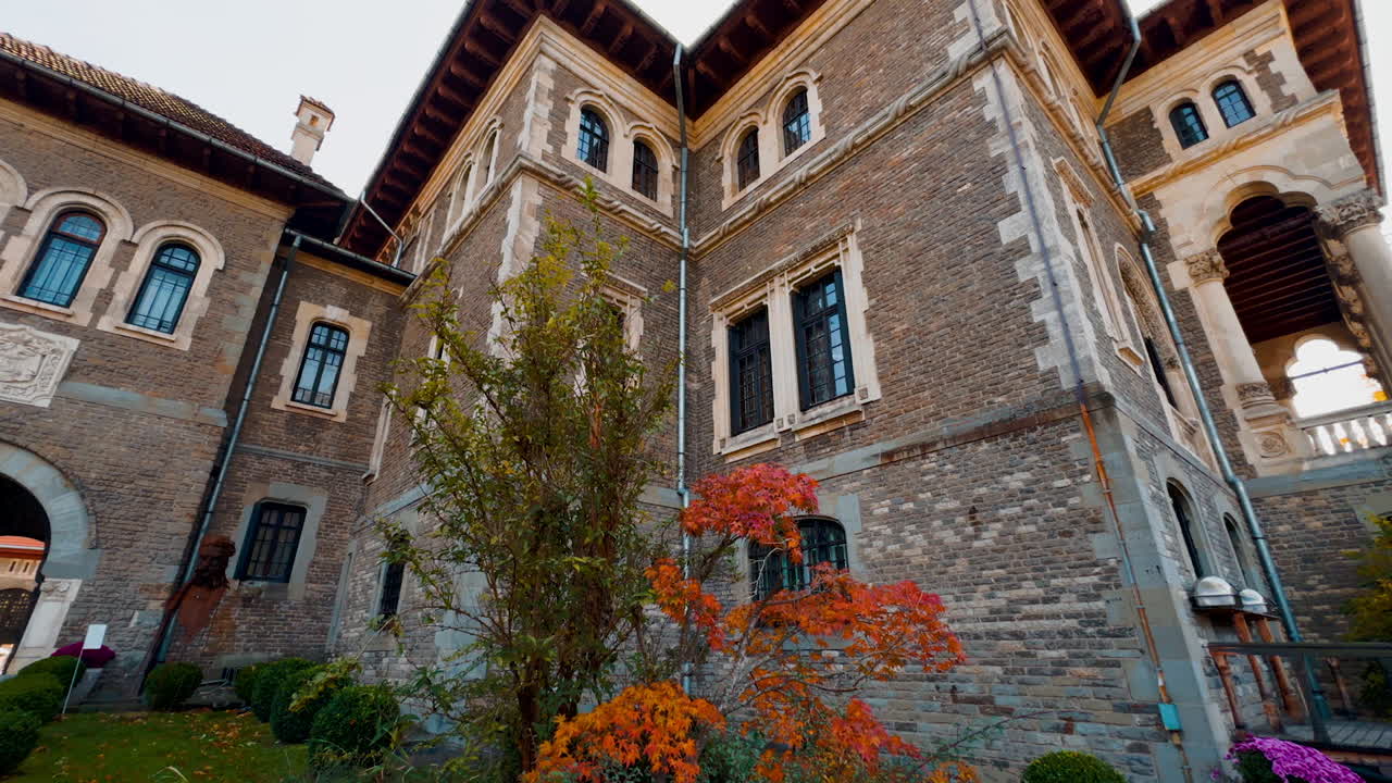 Big old-fashioned brick mansion interior. Beautiful decor of trees and bushes near the building.