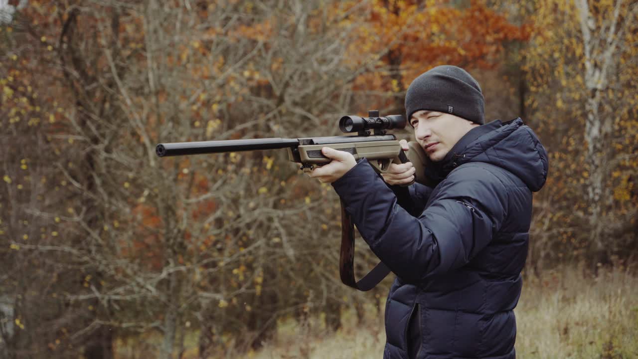 Hunter with gun on forest. Close up of the hunter man shooting with hunting rifle on nature