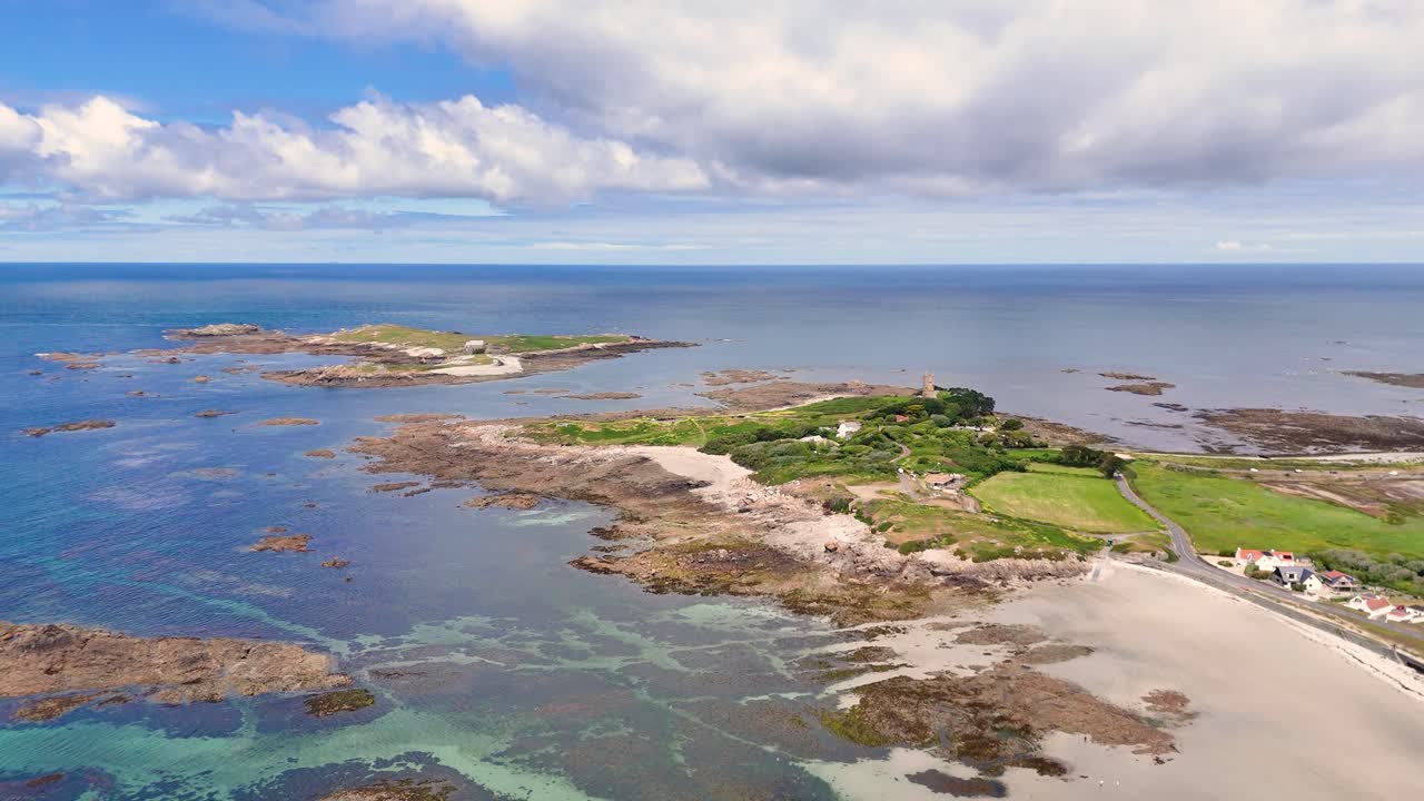 Guernsey. Flight towards Lihou Island on west coast of Island at half tide showing causeway and the crystal clear waters of this RAMSAR site on bright sunny day