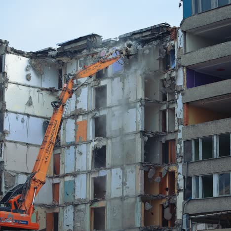 demolition of old residential building. destroying old concrete building using mechanical arm of bulldozer on construction site