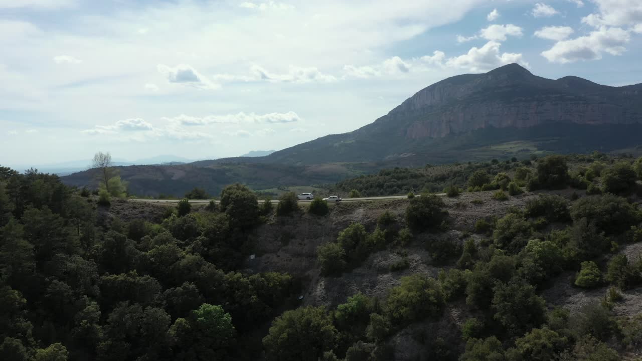 vehículo blanco colocado en la carretera al borde del acantilado con montañas de fondo