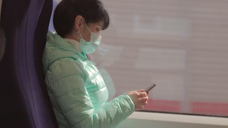 una mujer con una máscara médica protectora viaja en un tren durante la cuarentena de covid-19.