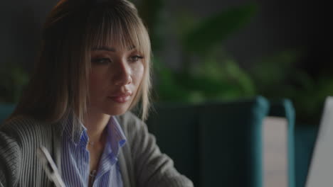 Young-Beautiful-smiling-Asian-business-woman-holding-a-coffee-and-laptop-Placed-at-the-wooden-table-at-the-office.-Woman-checking-mail-or-researching-while-telecommuting