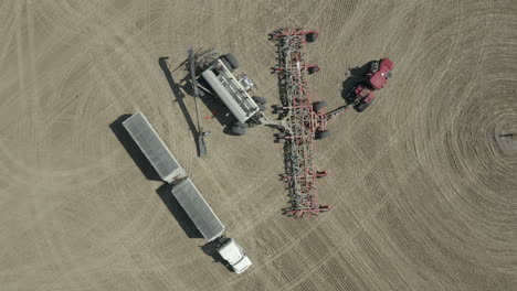Loading-Of-Seeds-To-Seeding-Tractor-At-The-Farm-In-Saskatchewan,-Canada---aerial-slowmo