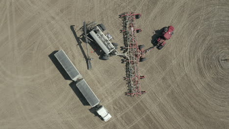 loading of seeds to seeding tractor at the farm in saskatchewan, canada - aerial slowmo