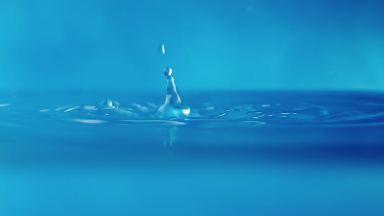 파란색 배경에 떨어지는 물방울과 함께 물 표면의 느린 모션 4k 비디오.