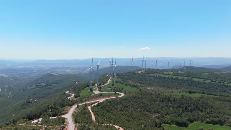 drone performs a smooth orbit around multiple wind turbines over a green mountainous landscape on a sunny day. renewable energy, clean technology and natural terrain combined in cinematic motion