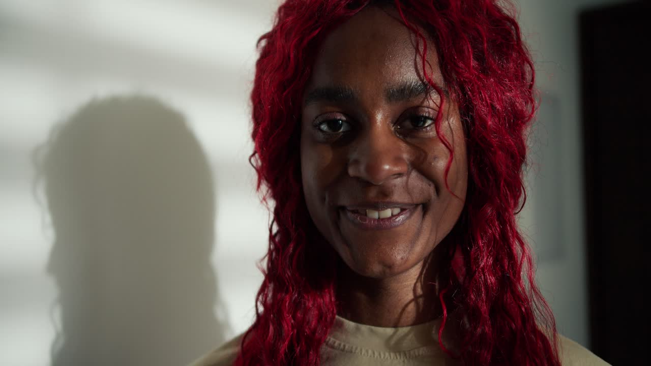 Ritratto di una donna afroamericana felice e spensierata con i capelli rossi, che sorride alla fotocamera.
