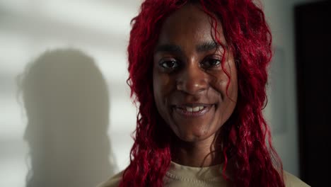 retrato de una feliz mujer afroamericana despreocupada con cabello de color rojo, sonriendo a la cámara